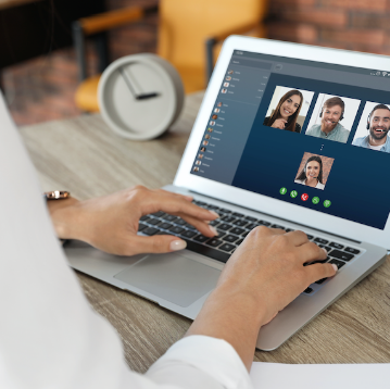 Person typing on laptop with videoconference on screen