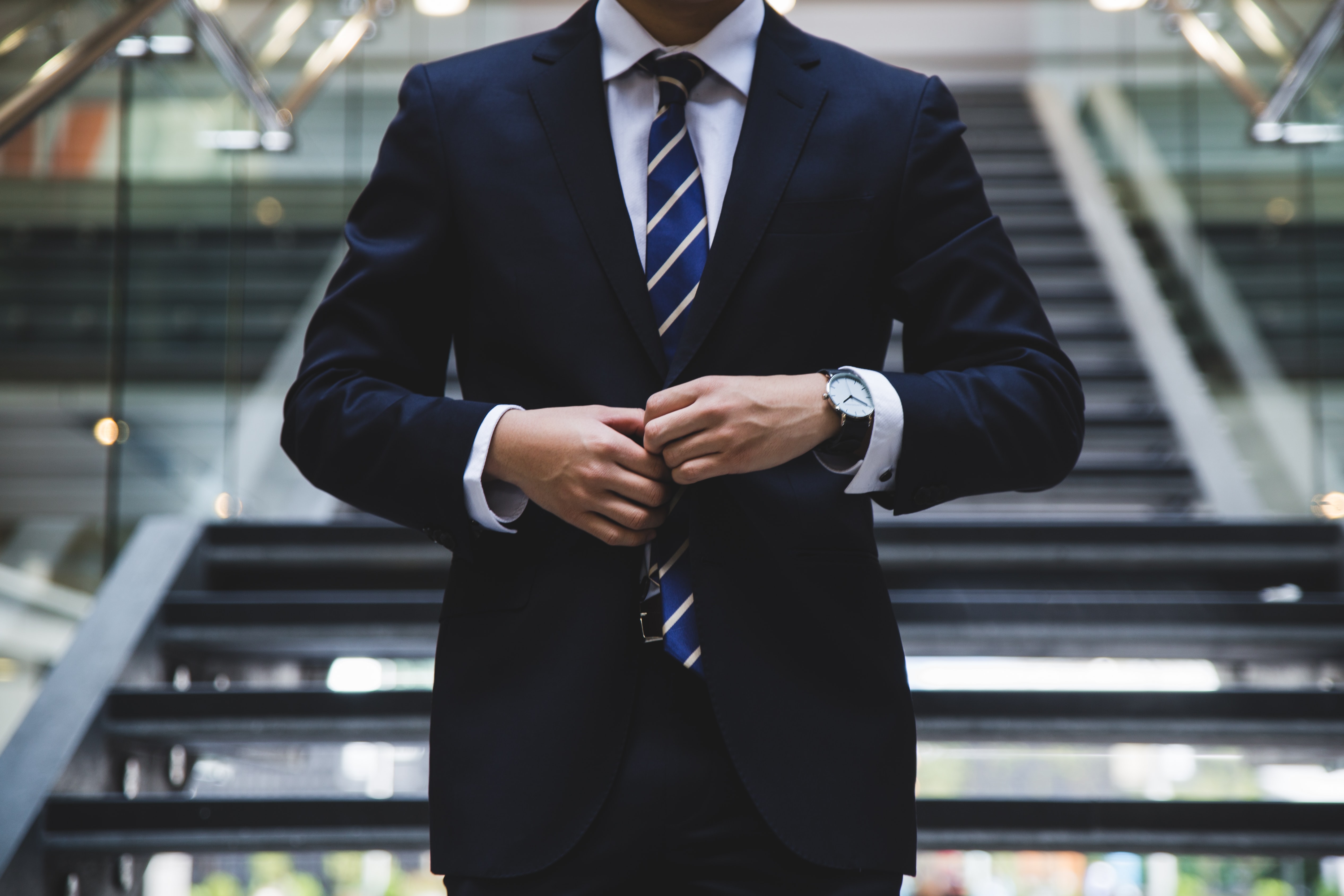 man walking outside down a flight of stairs adjusting his tie.