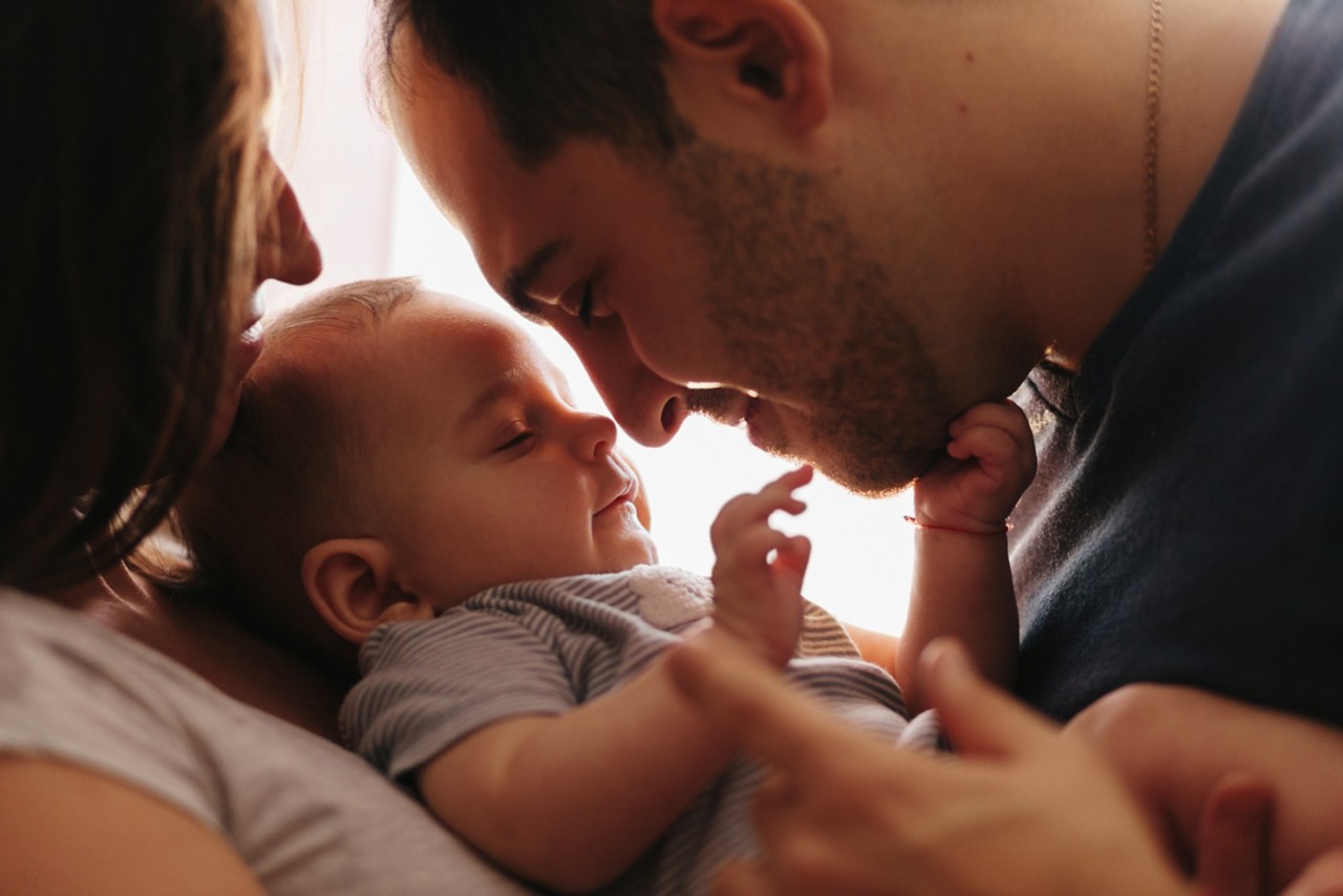 Baby with his parents playing on the bed. Happy family at home. Little boy 4 months old