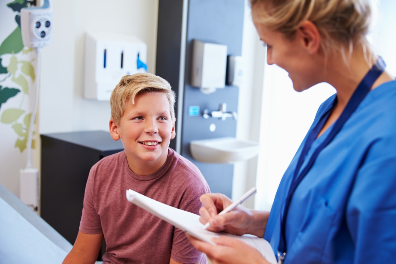 Teenage Boy And Doctor Have Consultation In Hospital Room