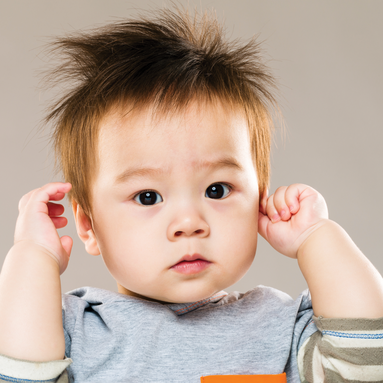 A young child holds their hands to their ears