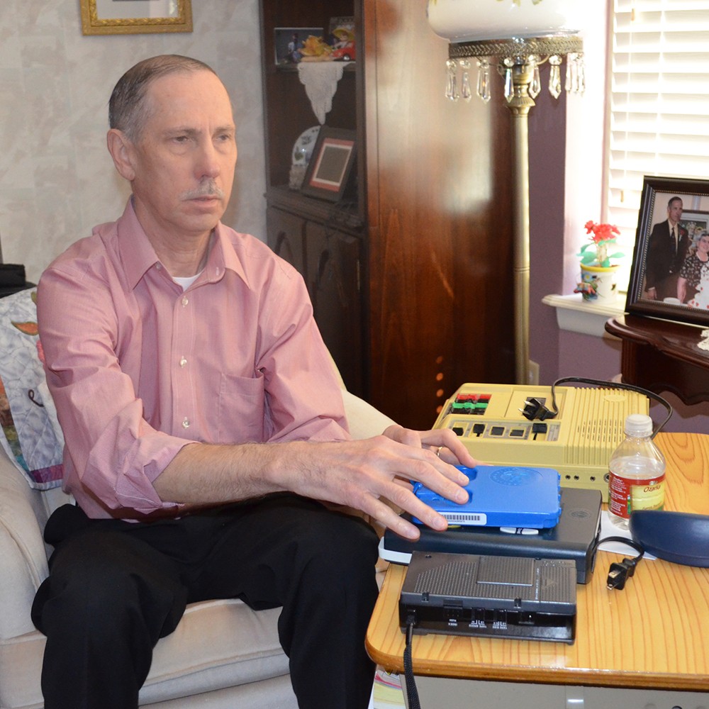 Meier holds up one of the digital cartridges that contains the audio book from the library