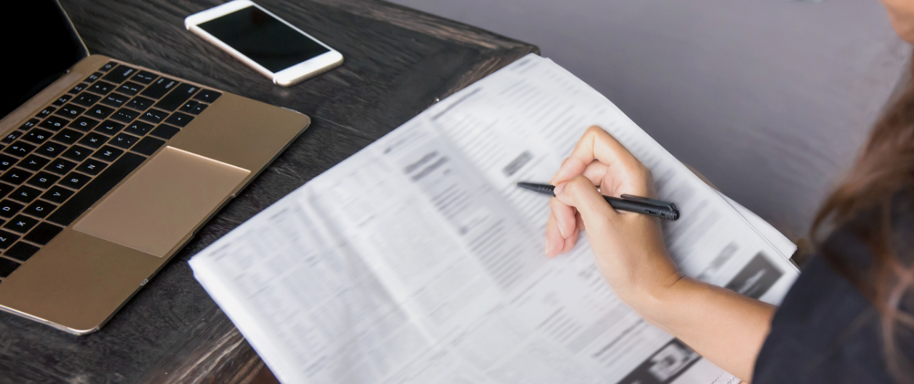 Person looking at a newspaper to a analyze job listings.