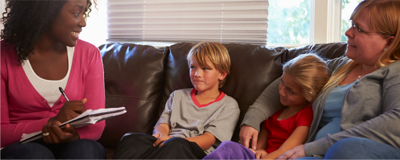 Smiling woman sitting with a family of three on a couch.