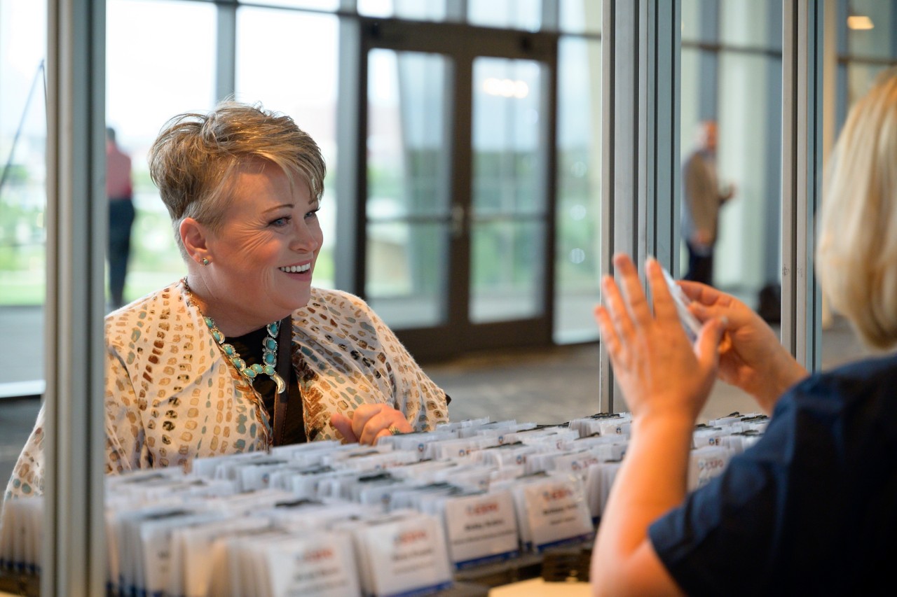 Woman smiling at event worker at check-in kiosk.