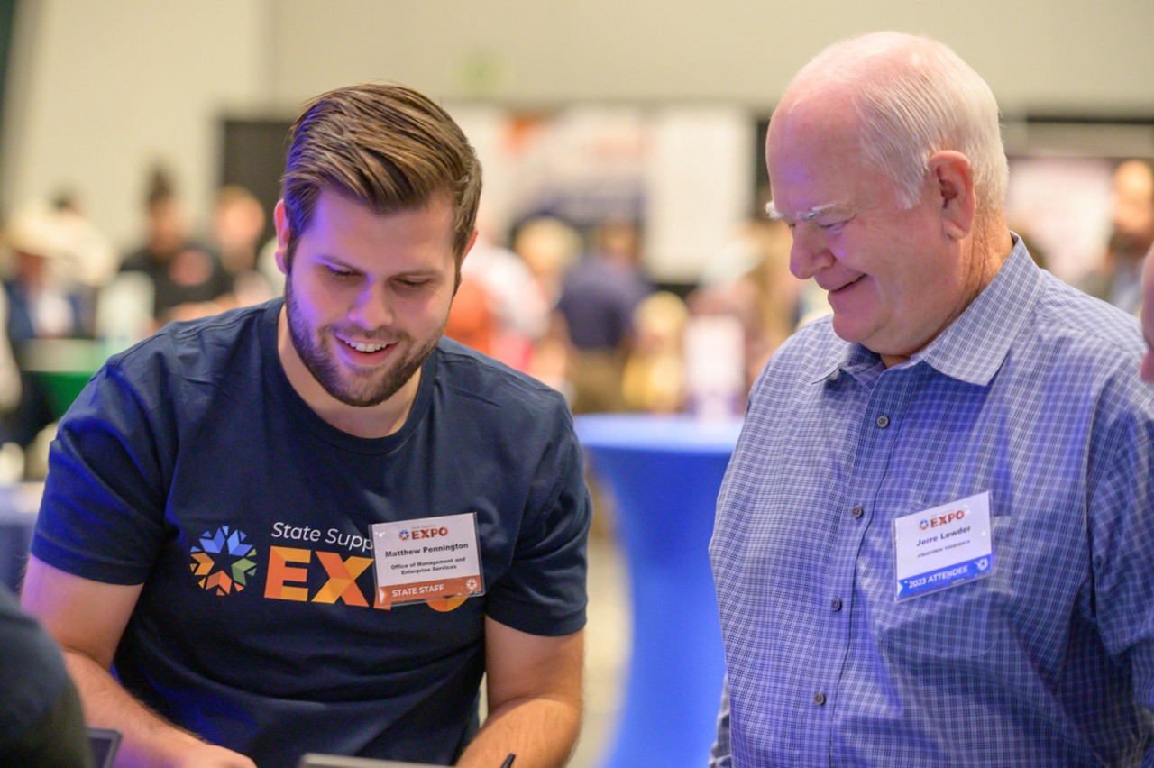 Matthew Pennington smiles while helping an attendee sign up as a state bidder.