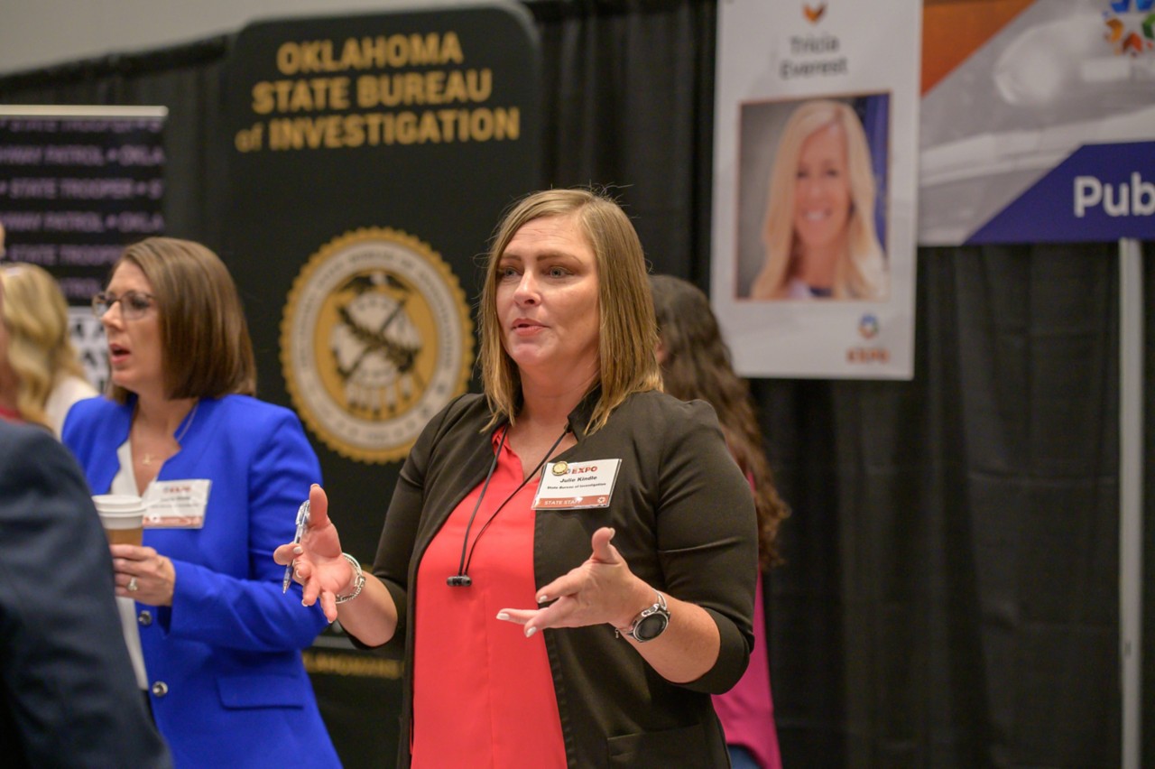 Julie Kindle talks with hands at the Public Safety cabinet booth.