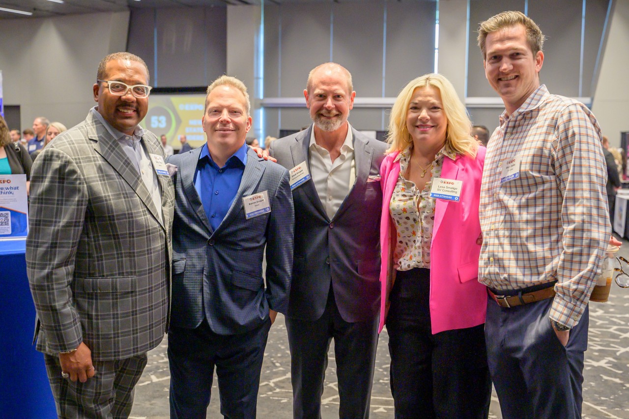 Five attendees smiling and standing in the ballroom.