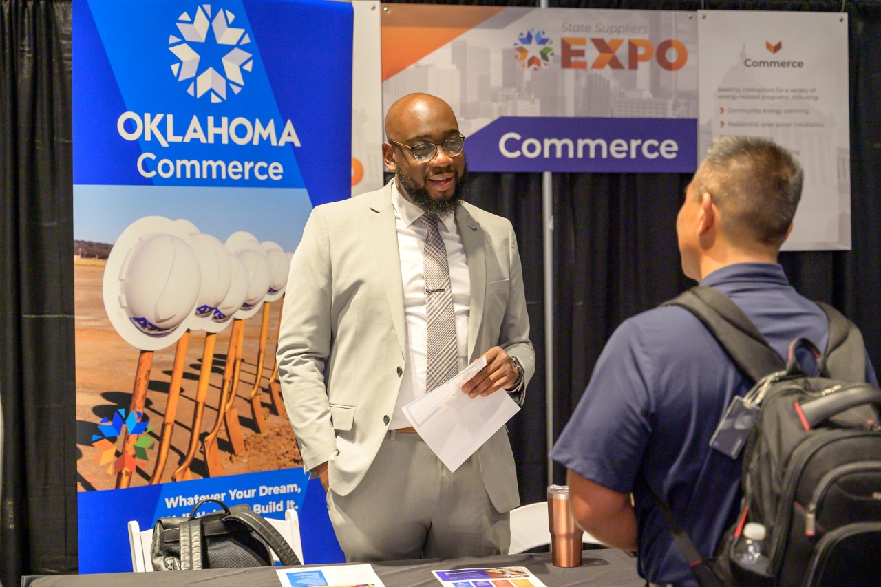 Cabinet staffer smiling and talking to an attendee at the Commerce booth.