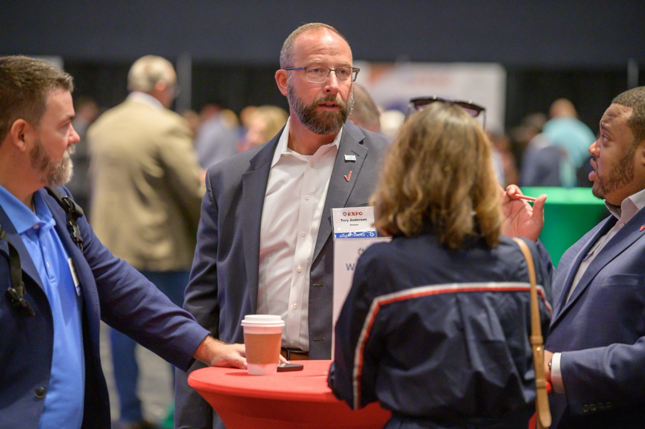 Attendees from Verizon talking at a bistro table in the ballroom.