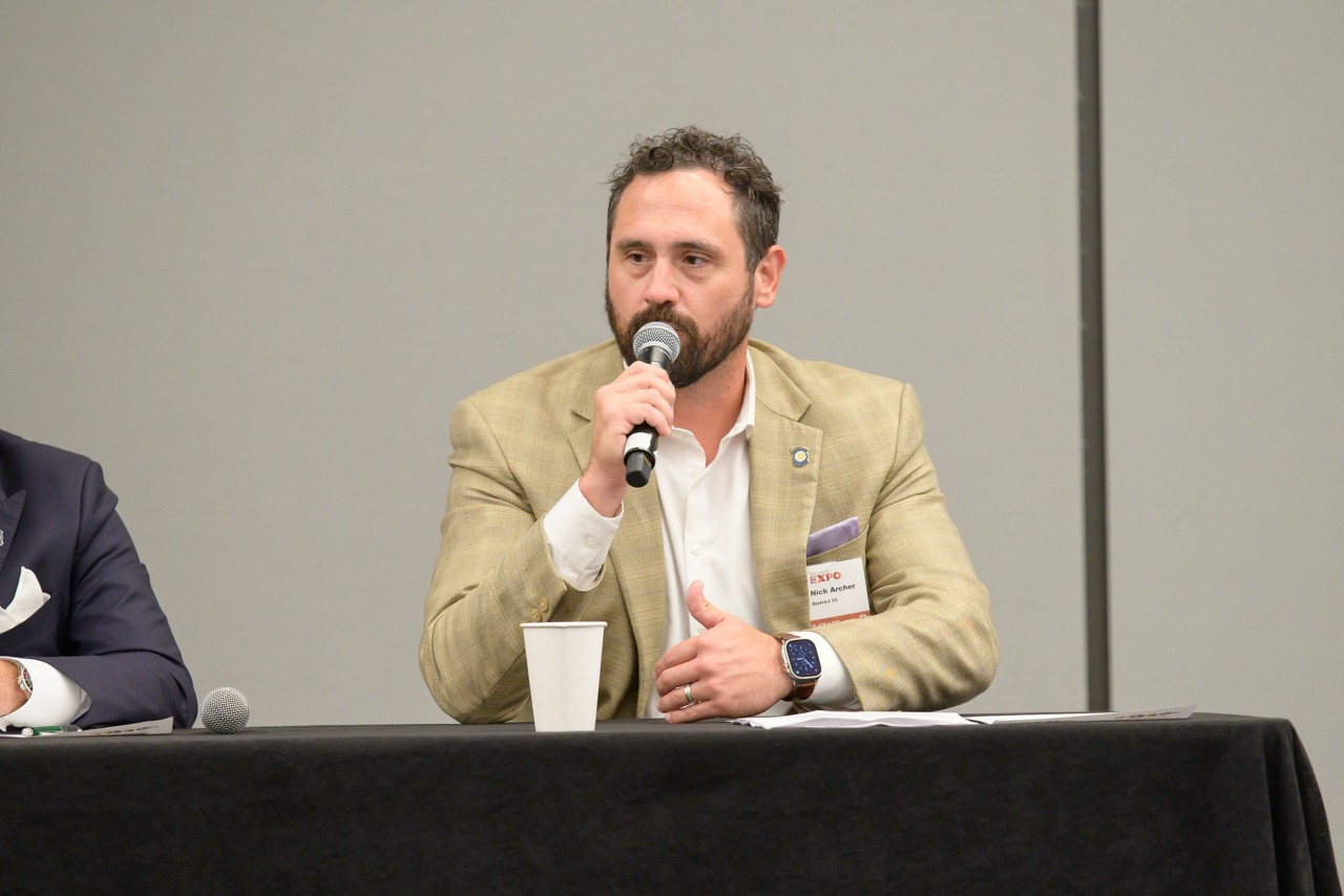 Rep. Nick Archer speaks with microphone during the legislative panel.