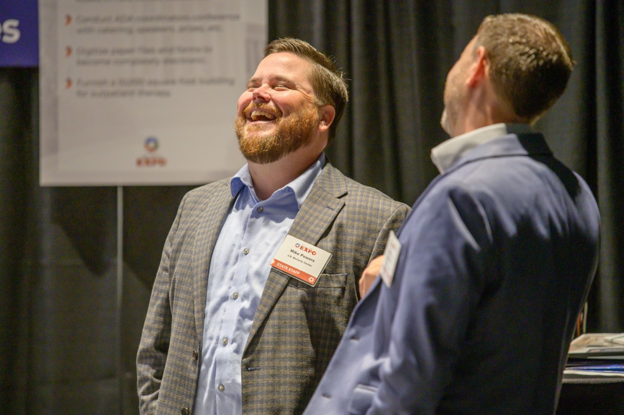 J.D. McCarty Center employee Mike Powers laughs in front of the Human Services booth.