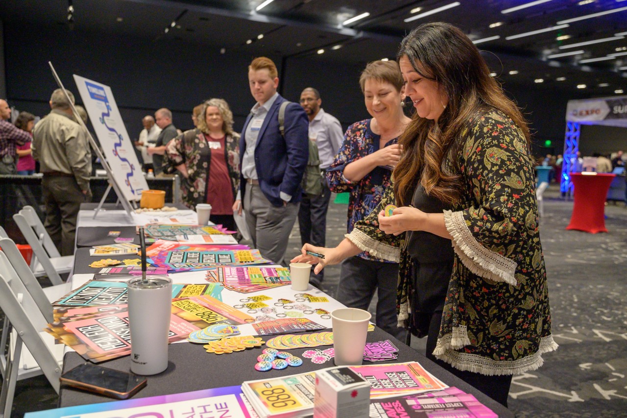 Attendees taking promotional materials from the Health and Mental Health cabinet booth.