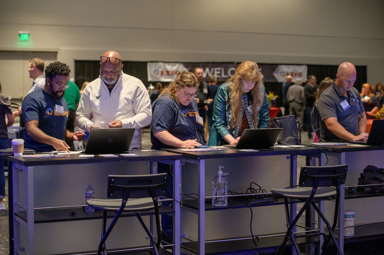 OMES staff helping three attendees sign up as state bidders at the Supplier Registration booth.