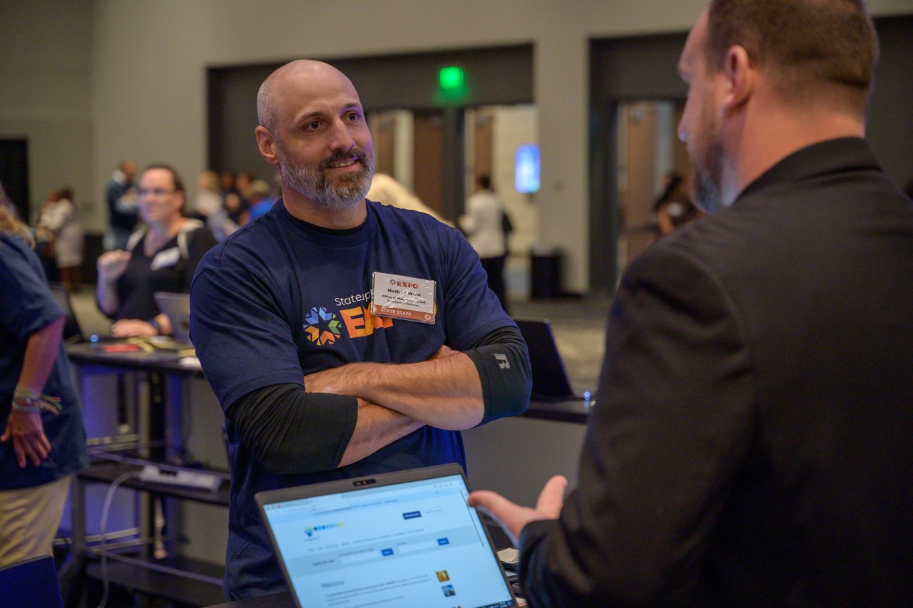 Nathan Wald talks to an attendee at the Supplier Registration booth.