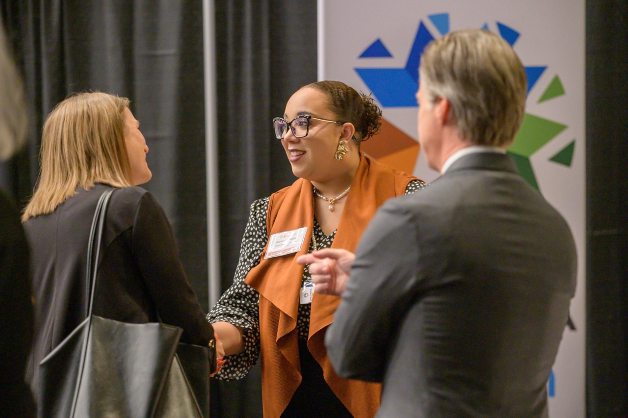 Oklahoma Human Services employee Madison Miller shaking hands with attendees at the Human Services cabinet booth.