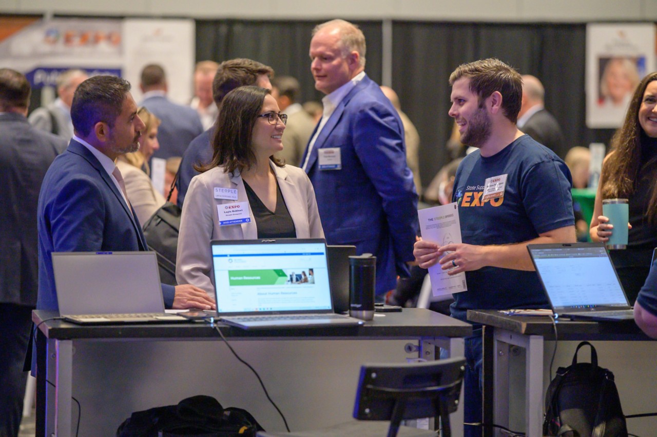 People standing and talking at the Supplier Registration booth.