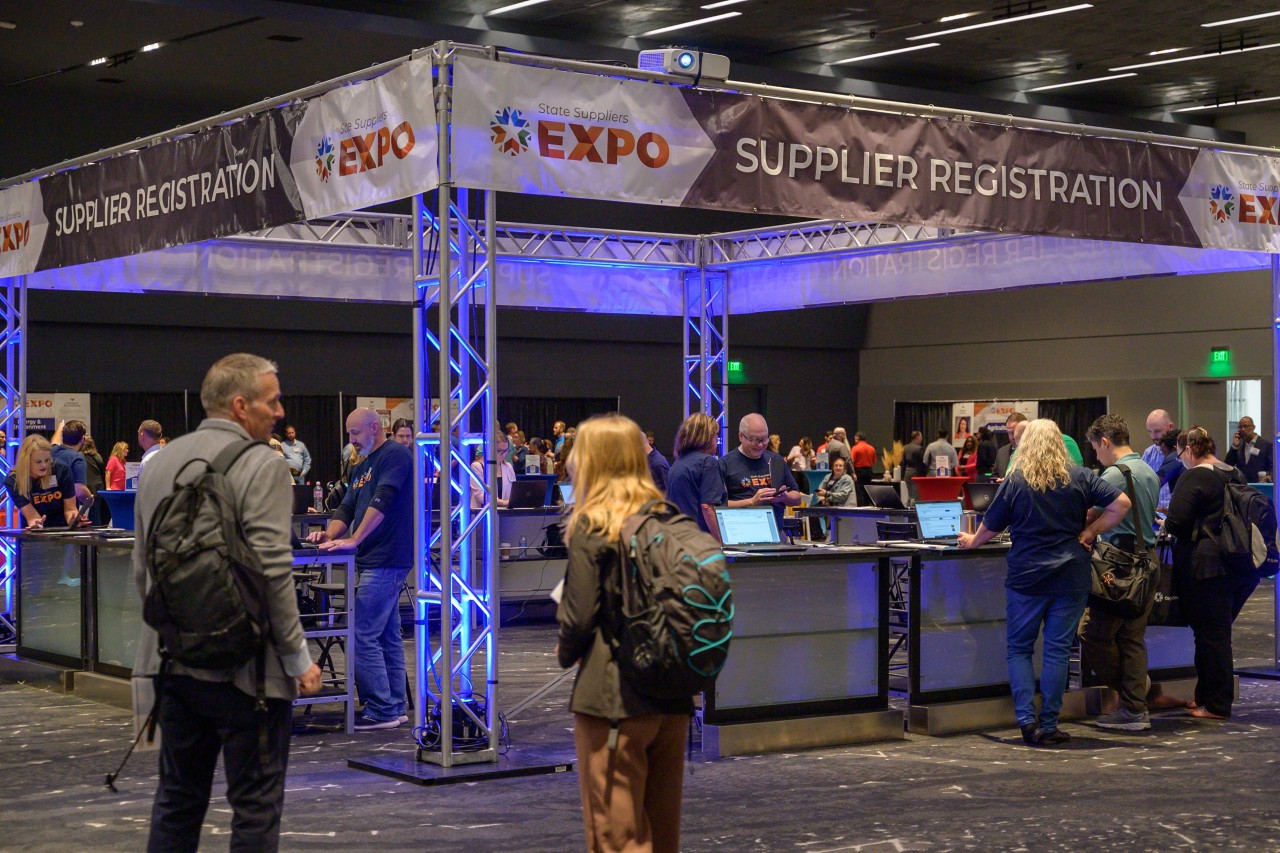 Attending businesses engaging with the Supplier Registration booth in the ballroom.