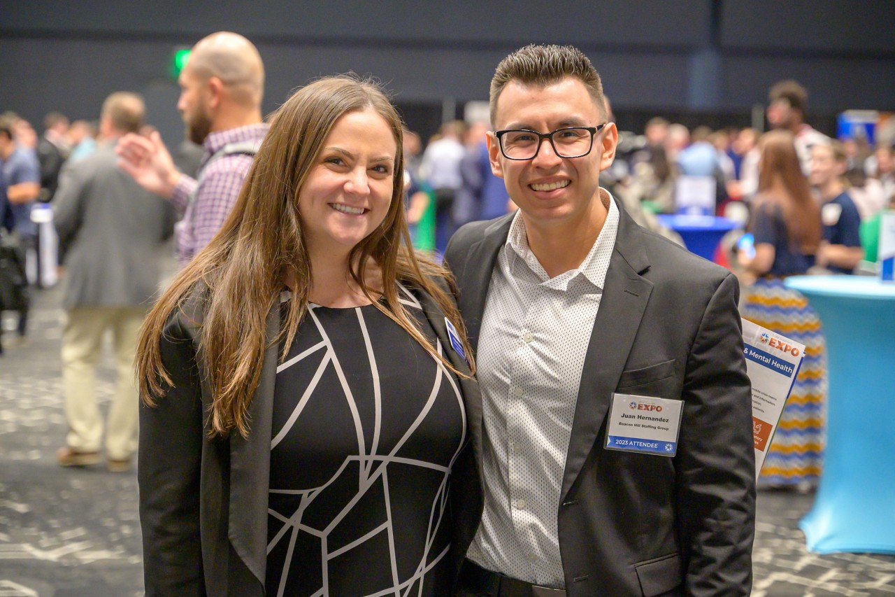 Two attendees smile and pose in the ballroom.