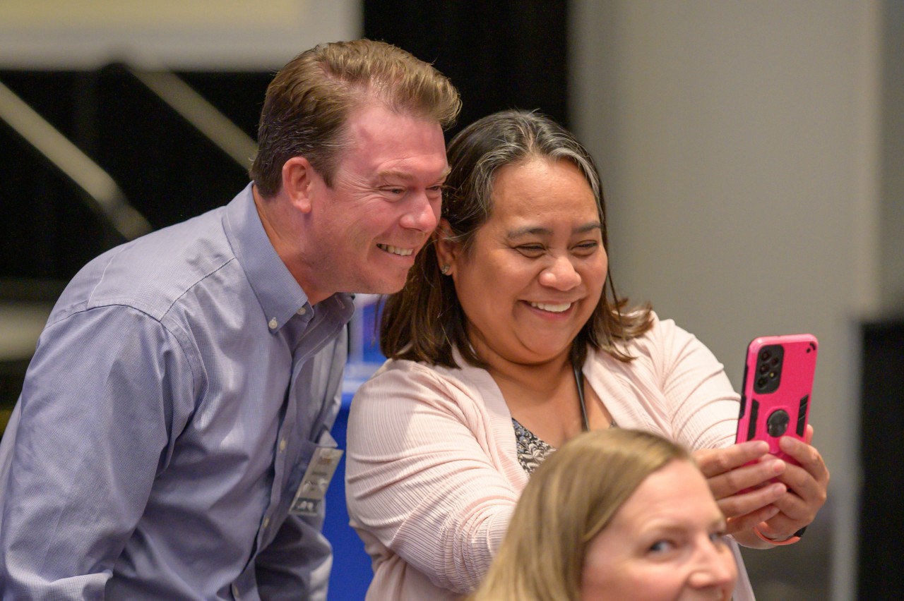 Two attendees smiling while taking a selfie.