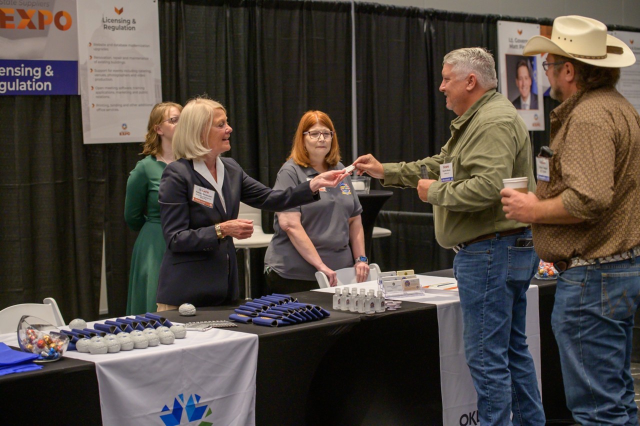 Secretary Susan Winchester takes a business card from an attendee at Licensing and Regulation cabinet booth.